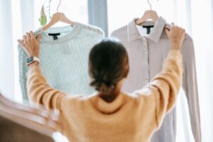 Woman holding up 2 blouses and trying to decide between them