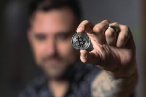 Hand holding a representation of a Bitcoin towards the camera