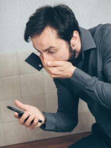 Shocked person looking at their phone when finding out they have been in a Ponzi Scheme